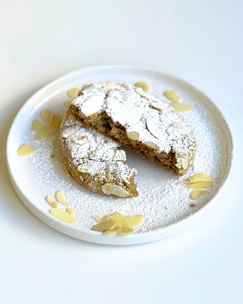 almond croissant protein cookie cut in half on a white plate