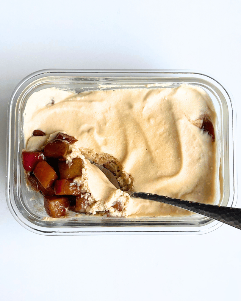 apple pie dessert in a glass bowl with a spoon digging into it.