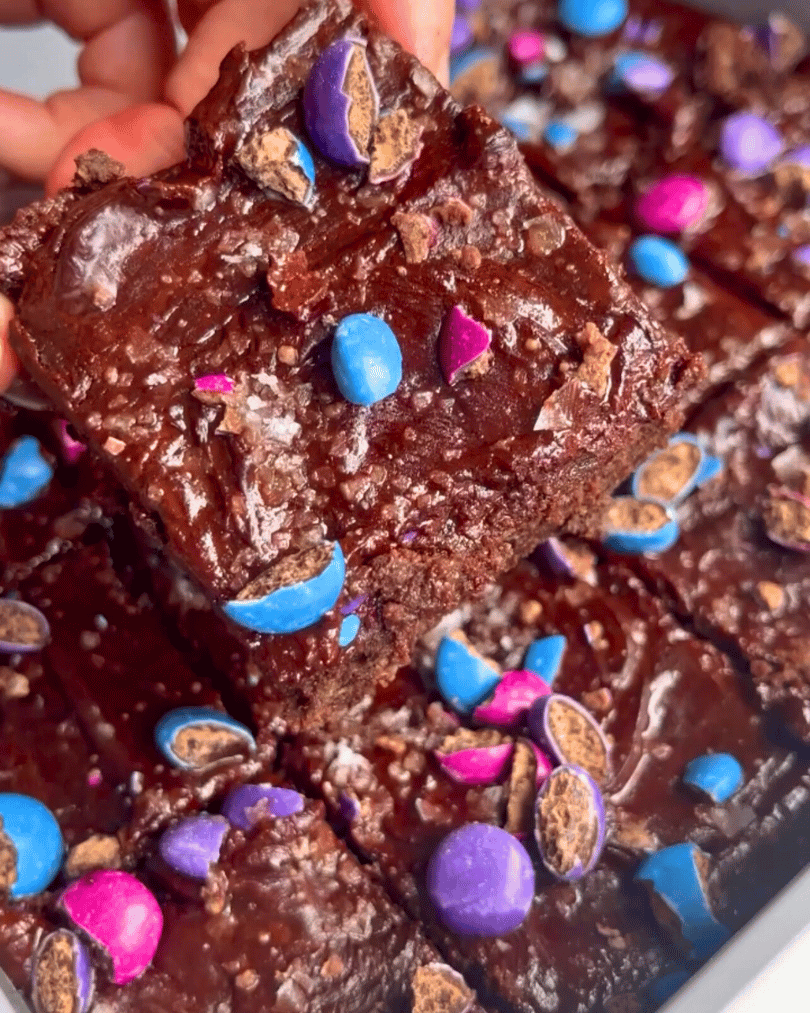 gluten free vegan brownies with chocolate frosting and pink, purple, and blue smarties