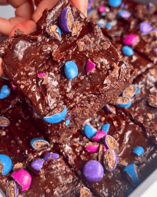 gluten free vegan brownies with chocolate frosting and pink, purple, and blue smarties
