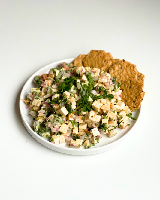 Tofu salad on a white plate with crackers on the side