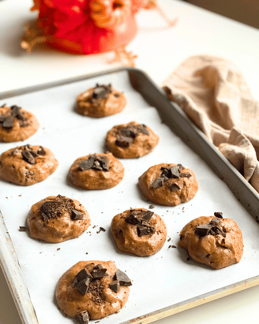 unbaked pumpkin spice cookies on a baking tray on a white counter with a pumpkin in the background