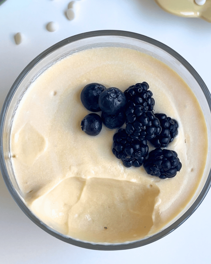 white chocolate vanilla protein pudding in a glass jar with berries on top