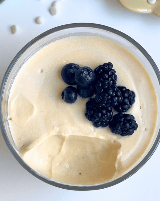 white chocolate vanilla protein pudding in a glass jar with berries on top
