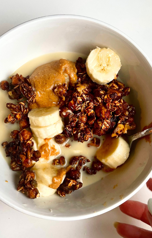 Vegan Granola with banana, peanut butter and plant based milk in a white bowl