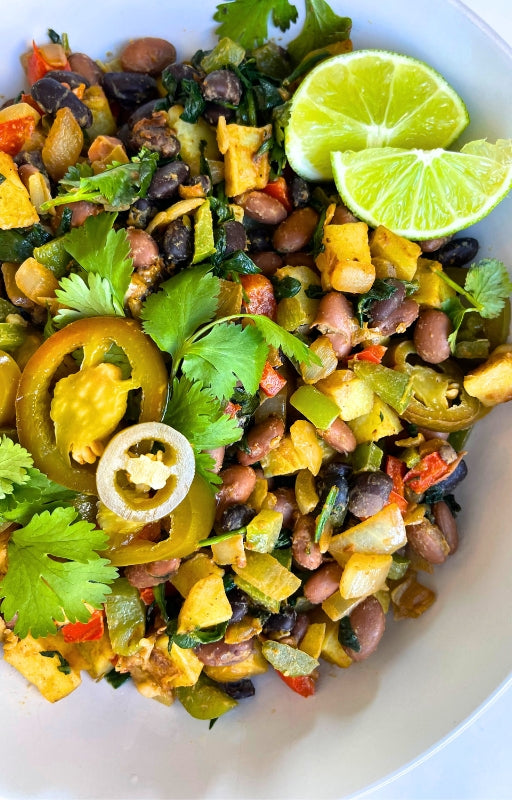 Mexican hash breakfast bowl topped with pickled jalapeño, cilantro and limes
