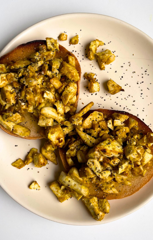 Roasted tofu and bagels on a beige plate on a white background