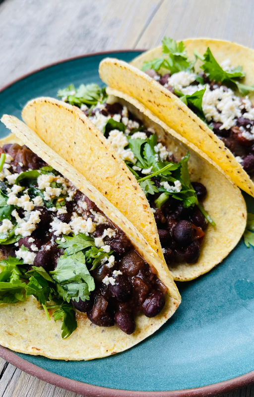 three vegan black bean tacos on a green plate