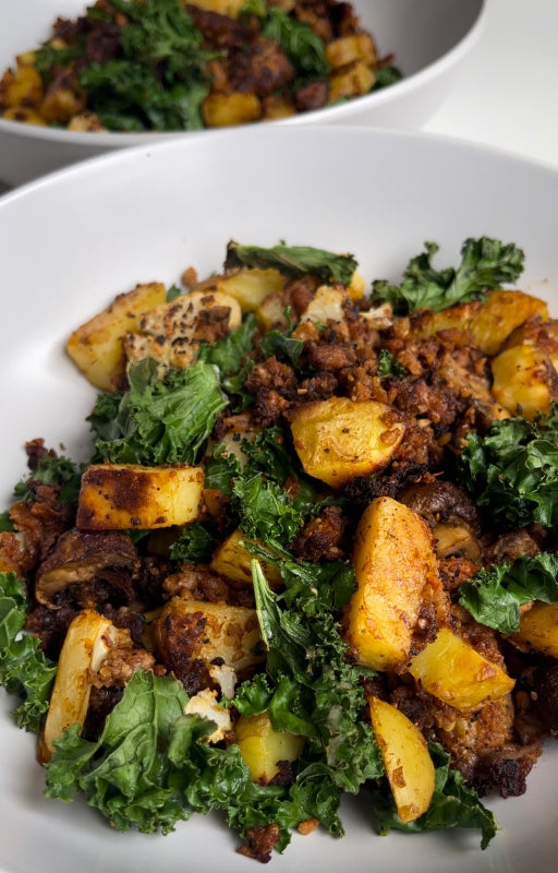 two High protein vegan breakfast with potatoes kale and veggie crumble in white plates