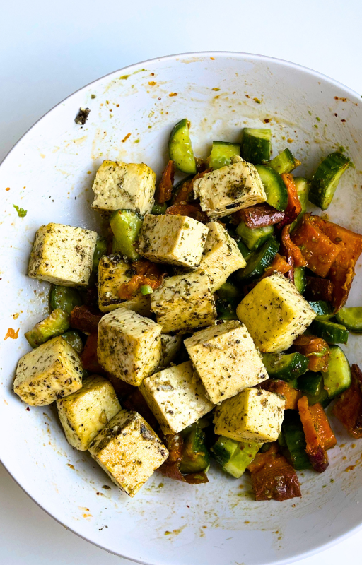 Vegan greek salad with tofu cubes on a white plate