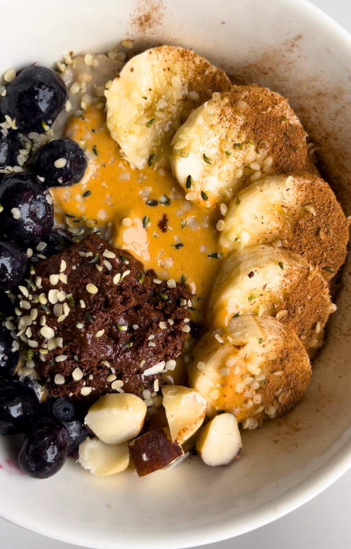 A protein bowl topped with banana, cinnamon, peanut butter, blueberries and hemp hearts