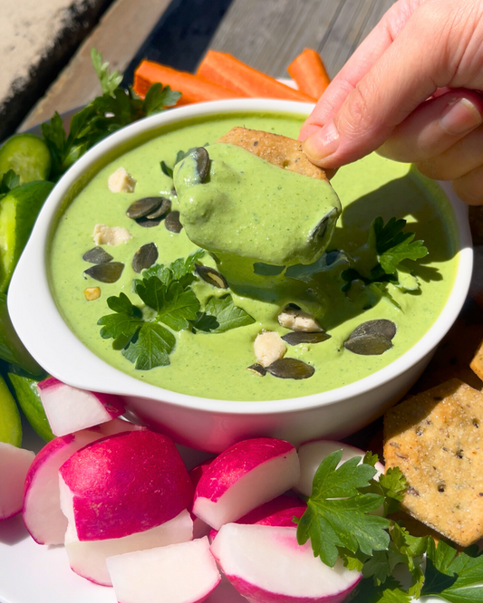 green goddess dip with carrot, radish, cucumbers and crackers on a plate.