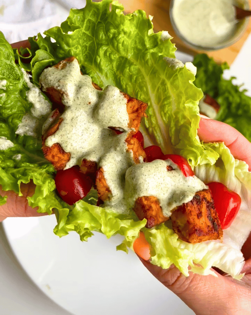 tempeh bacon lettuce wrap being held by two hands up close