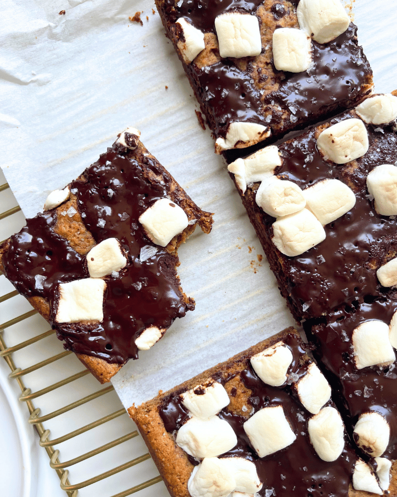 s'mores cookie bars on white parchment paper over a gold cooling rack.