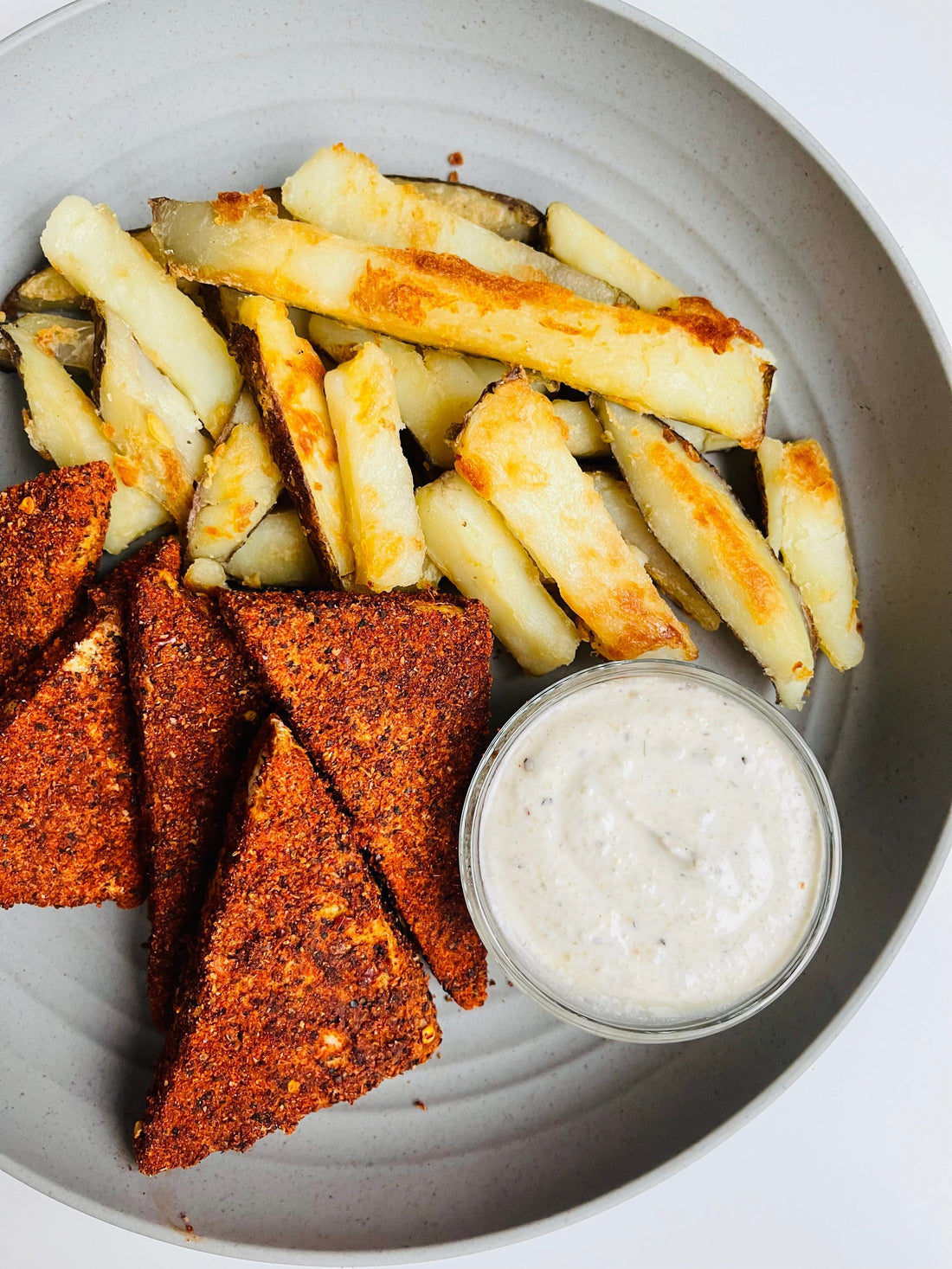 blackened vegan chicken tenders and baked fries on a plate
