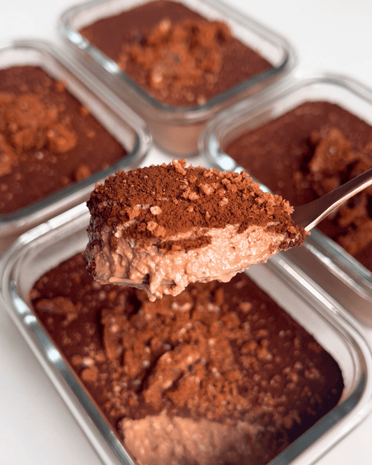 brownie batter overnight oats in glass jars with a spoon holding up the oatmeal in the centre