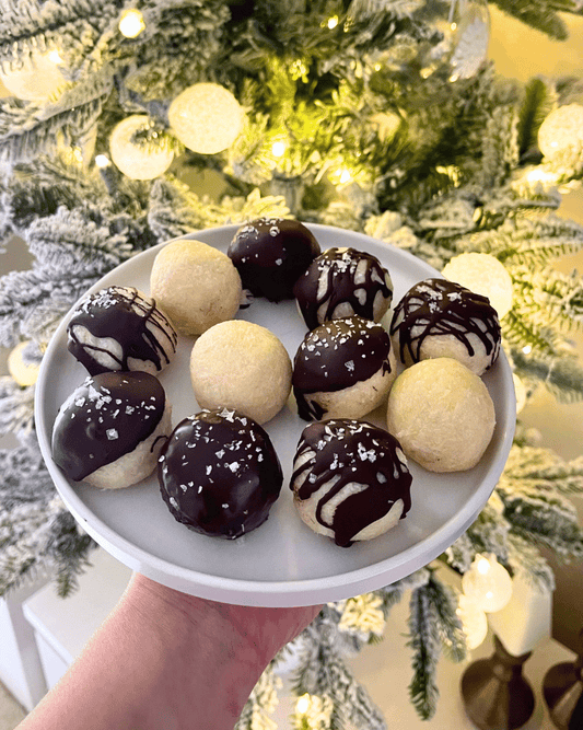 chocolate covered coconut balls on a white plate in front of a Christmas tree
