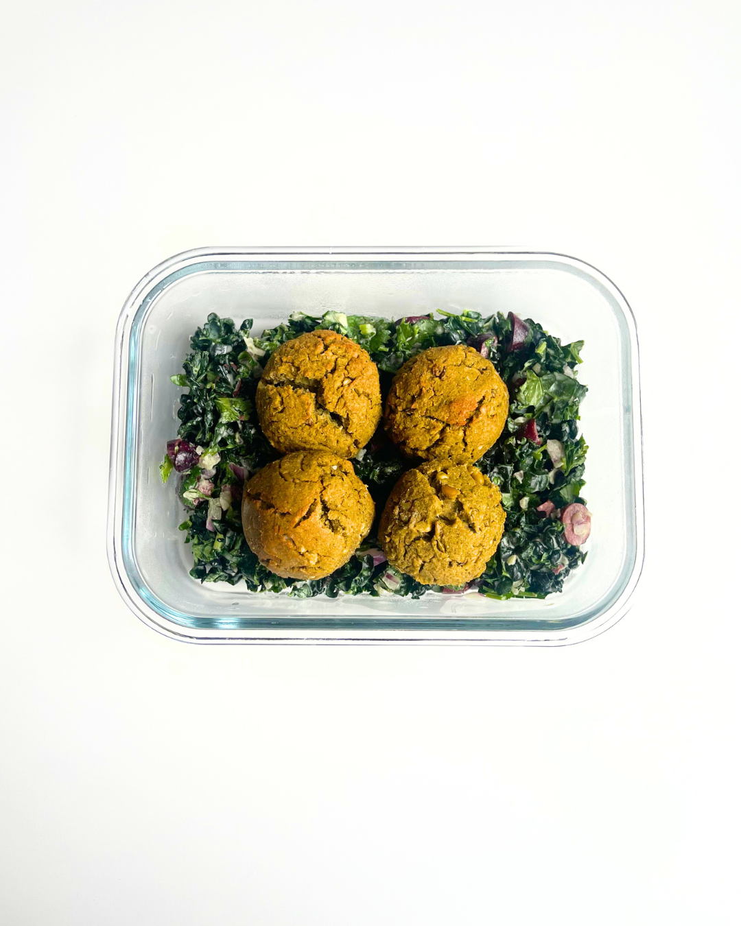 Falafel recipe over kale salad in a meal prep container. 