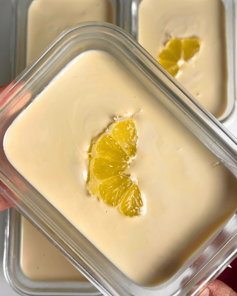 Glass container of lemon flavoured overnight oats with a lemon slice on top