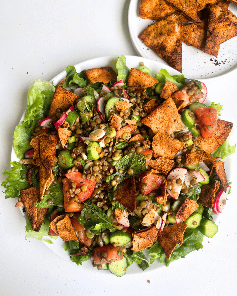 lentil fattoush salad on a white plate with another plate of pita chips