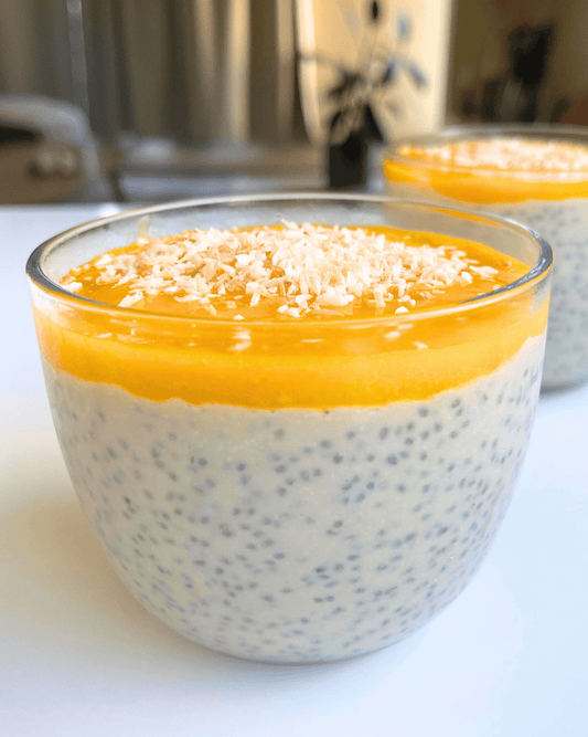 Two glasses of mango coconut chia pudding on a white surface.