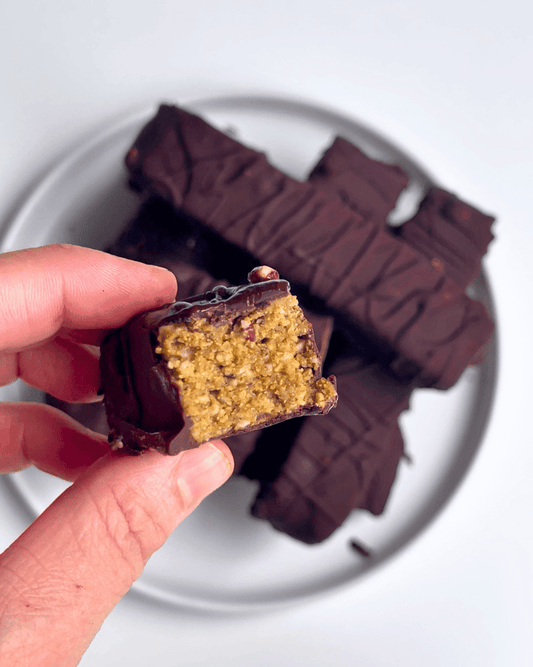 a hand holding a half eaten chocolate covered protein bar made without protein powder