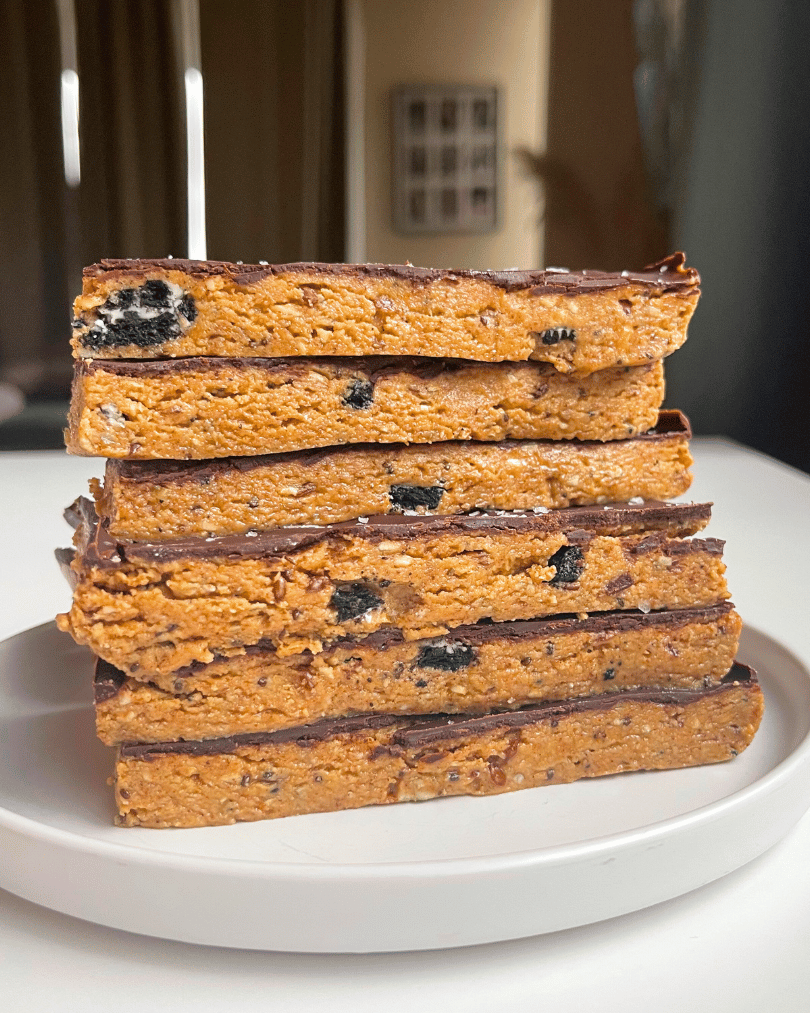6 peanut butter chocolate protein bars stacked on top of one another on a white plate