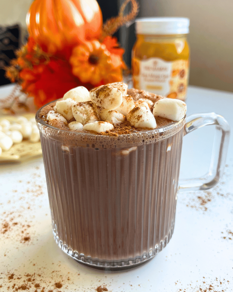 pumpkin spice hot chocolate with marshmallows and cinnamon on top, on a white counter