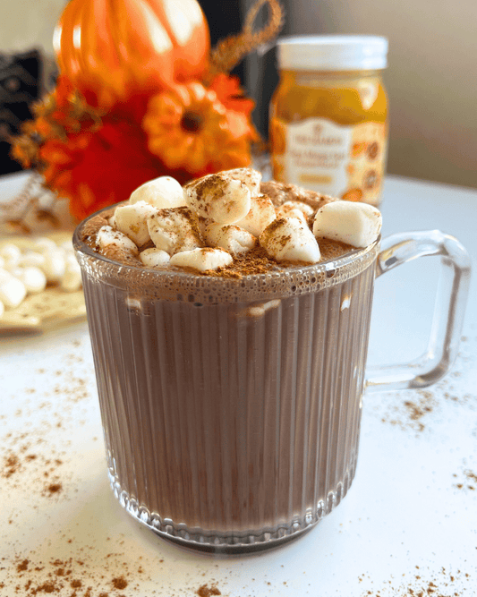 pumpkin spice hot chocolate with marshmallows and cinnamon on top, on a white counter