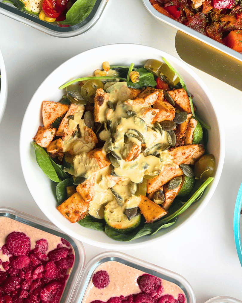 spinach salad with blackened tofu in a white bowl