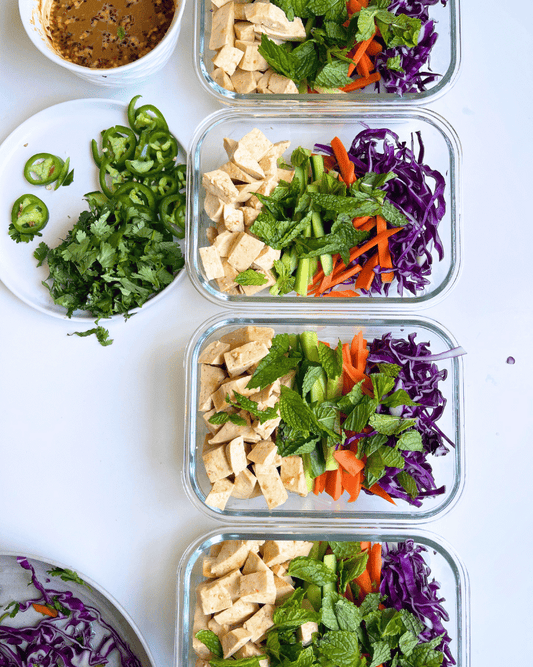 spring roll salad meal prep in 4 glass containers on a white surface.
