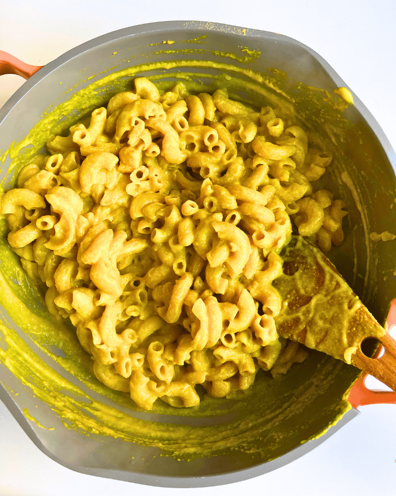 elbow pasta noodles with cheese sauce in a grey pan with a pink handle