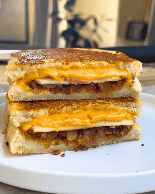 vegan grilled cheese cut in half and stacked on top of each other on a white plate