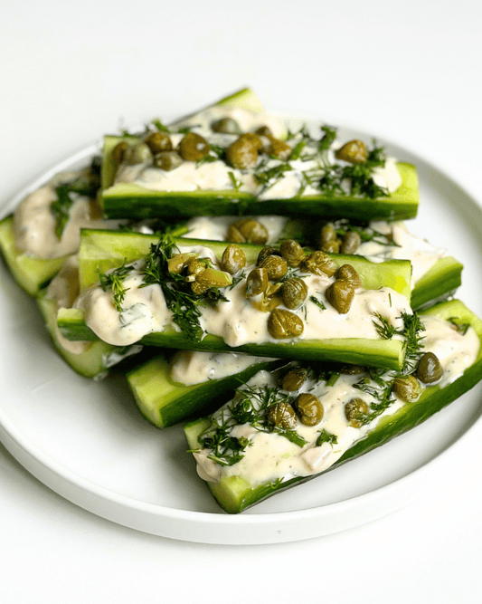 vegan smoked salmon dip in cucumber boats on a white plate