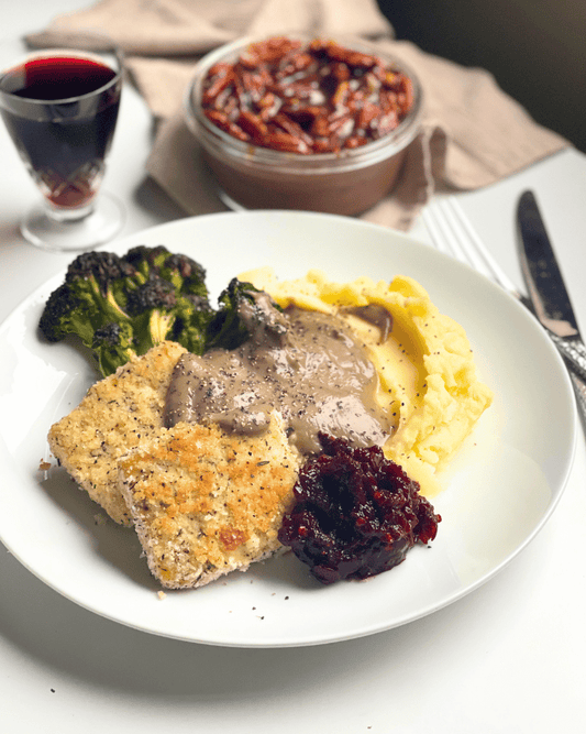 vegan thanksgiving dinner plate with a glass of cherry juice and a chocolate pecan pudding in the back