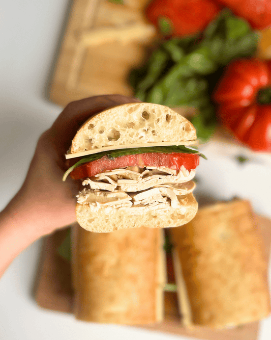 vegan turkey deli slices sandwich being held by a hand so you can see the sandwich fillings