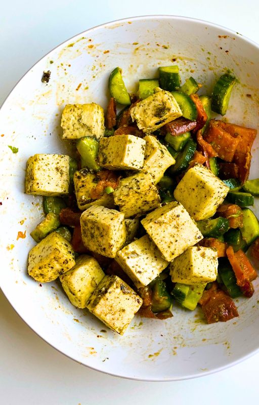 Chopped veggie salad with tofu in a white bowl on a white background