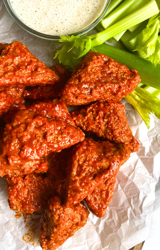 Stack of spicy tofu wings with a side of vegan white dipping sauce and celery