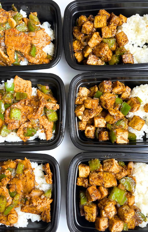six vegan rice bowls with black pepper seitan and back pepper tofu in black plastic meal prep containers